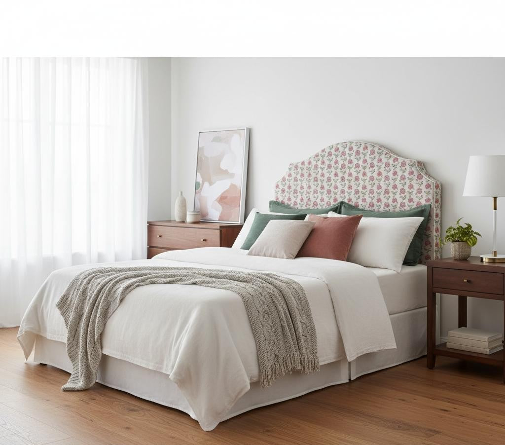 Modern bedroom with a white bed and floral fabric headboard, styled in soft natural light with crisp bedding and a wooden bedside table.